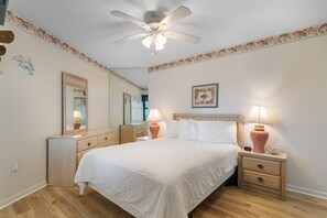 A bedroom with a bed, nightstands, a ceiling fan, a dresser, and a mirror. - Oceanfront Condo with Resort Pool, Hot Tub and Indoor Pool — Garden City Beach, (Garden City Beach)