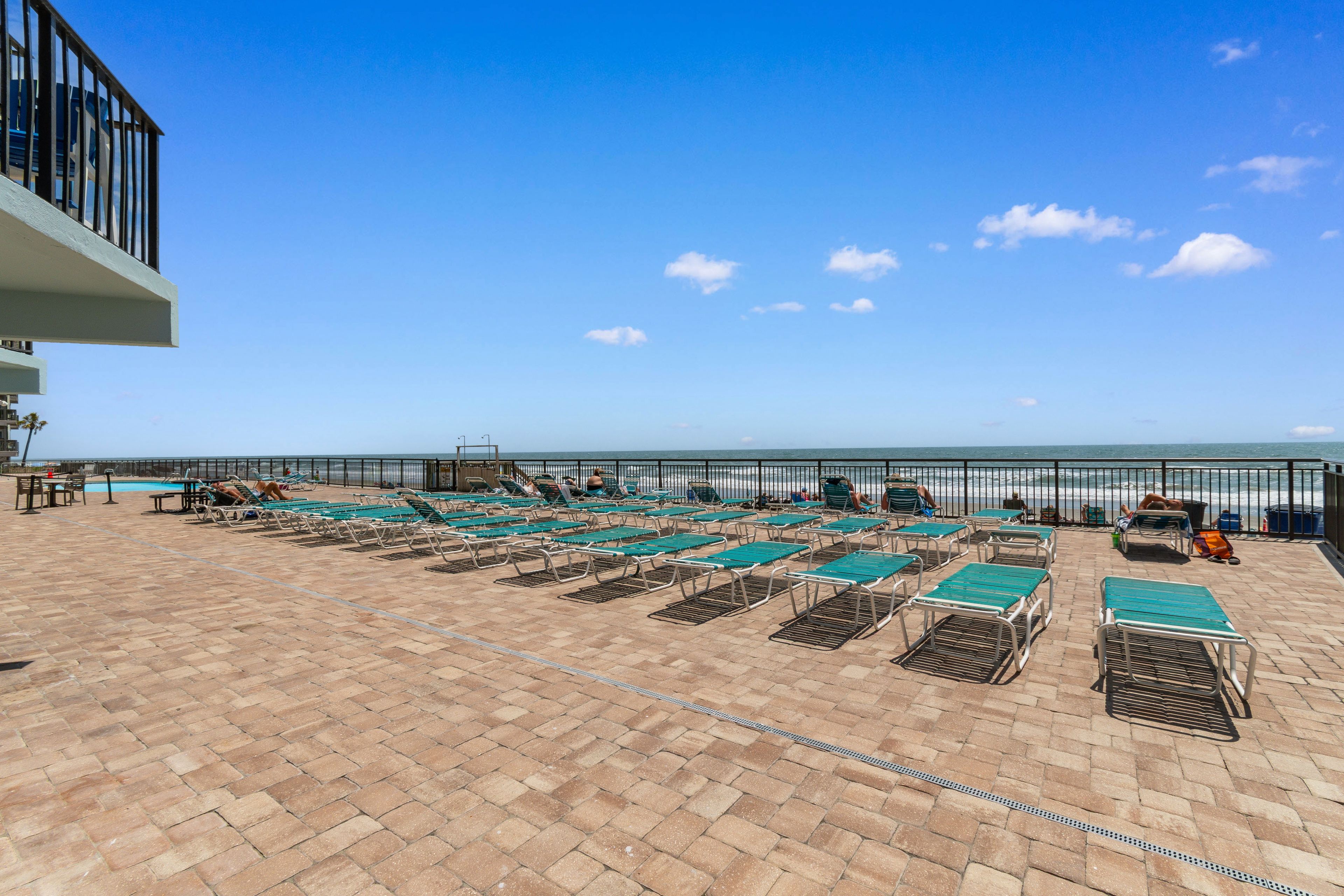 Eine Dachterrasse mit Liegestuhlreihen und Blick auf das Meer.