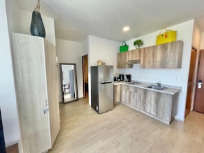A modern kitchen with a refrigerator, microwave, and coffee maker. - Apartment in El Chante Lake View (Chantepec)