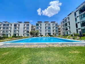 A modern building with a swimming pool in front. - Apartment in El Chante Lake View (Chantepec)