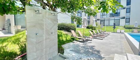 A poolside area with lounge chairs and a modern building in the background.