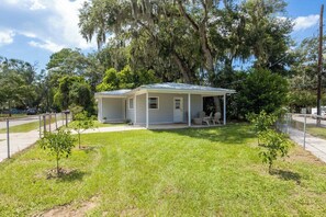 A small, single-story house with a covered porch and a fenced yard. - Orange Grove home - fully renovated minutes from downtown (St. Augustine)
