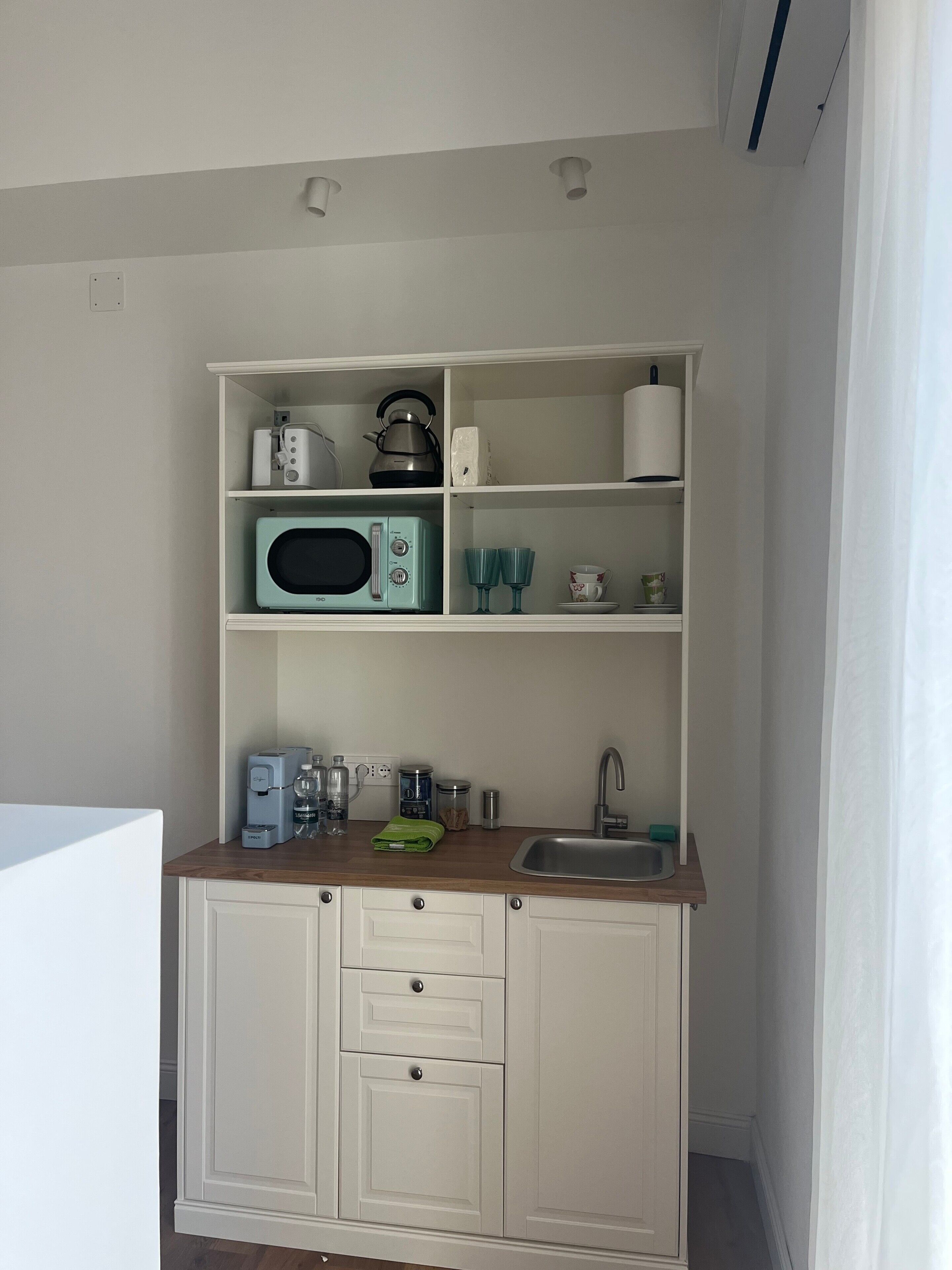 A compact kitchenette with a microwave, kettle, and a small sink.