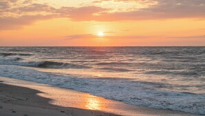 Una platja amb onades, un capvespre i un cel clar.