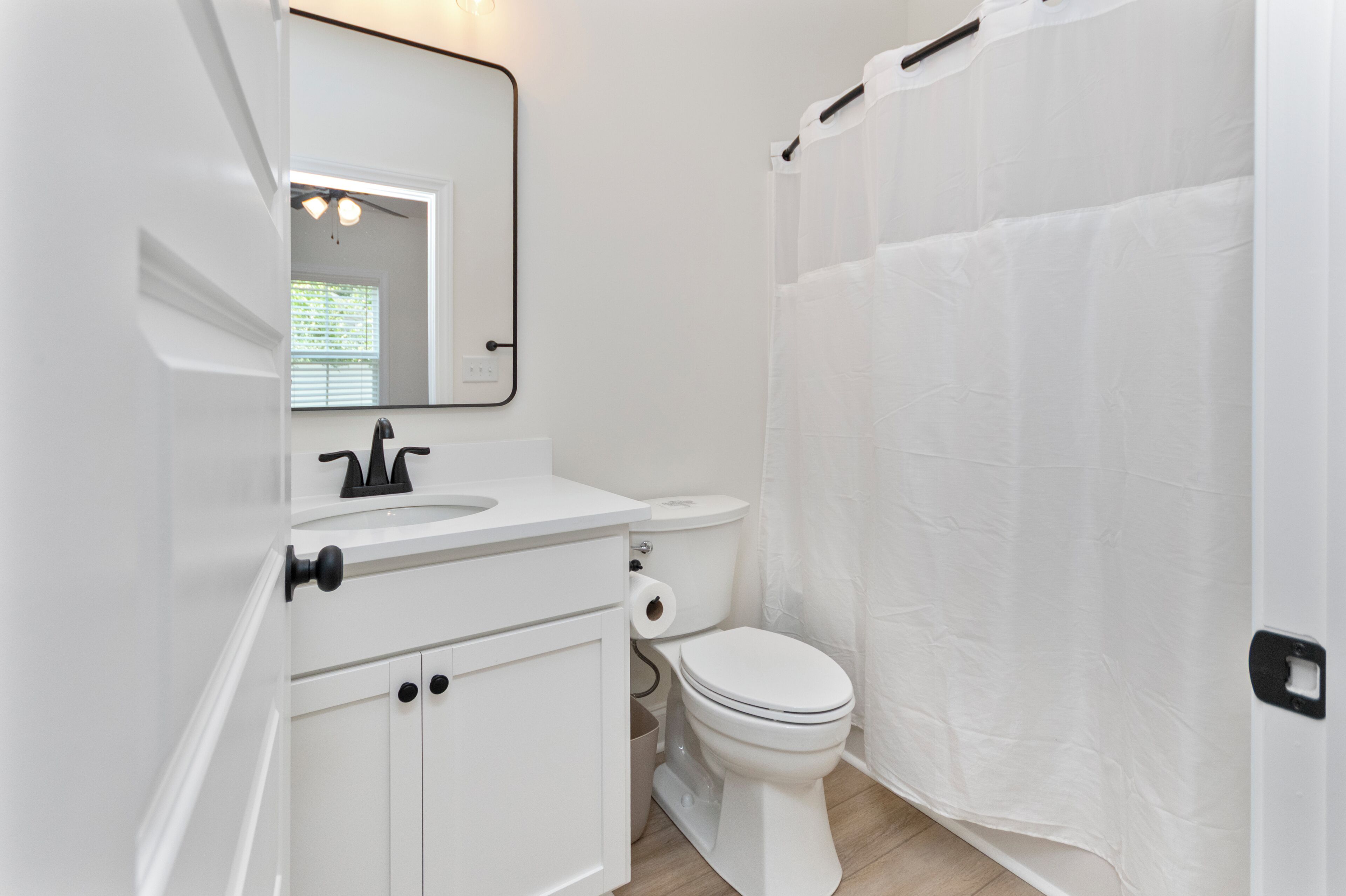 Un baño con lavamanos, inodoro y cortina de ducha blancos.