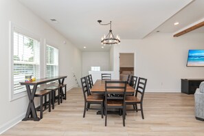 Ein geräumiger Essbereich mit Holztisch und Stühlen, einer Kristallleuchter und Blick zur Küche im Hintergrund.
