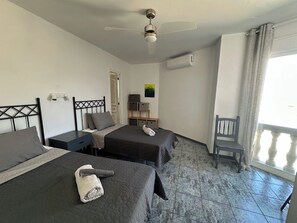 Ein Hotelzimmer mit zwei Betten, einem Deckenventilator, einer Klimaanlage, einem Stuhl und einem fenster mit Vorhängen.