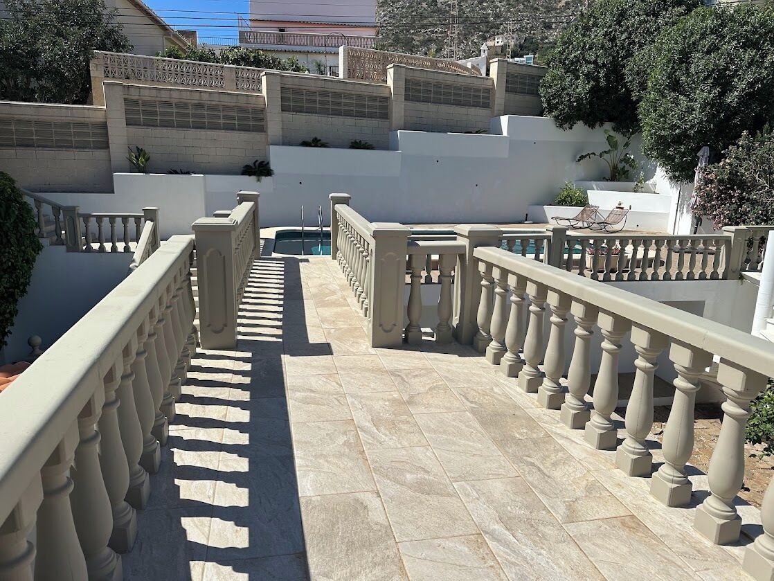 A staircase leading to a terrace with a balustrade, surrounded by walls and greenery.