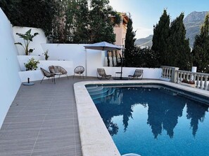 Ein Pool mit geschwungener Kante, umgeben von einer weißen Mauer und einer Holzterrasse.