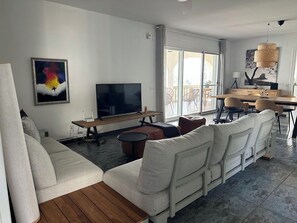 Ein modernes Wohnzimmer mit Sofa, Fernseher und Essbereich.