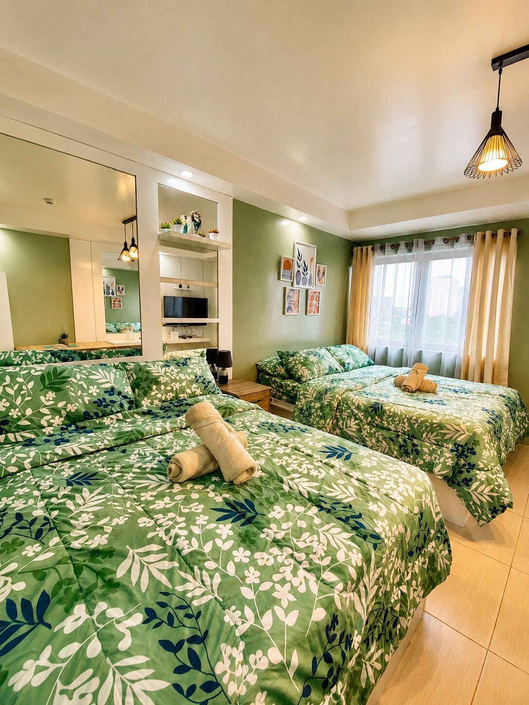 Een hotelkamer met twee bedden, een televisie, een plank met decoratieve objecten en kunst aan de muur.
