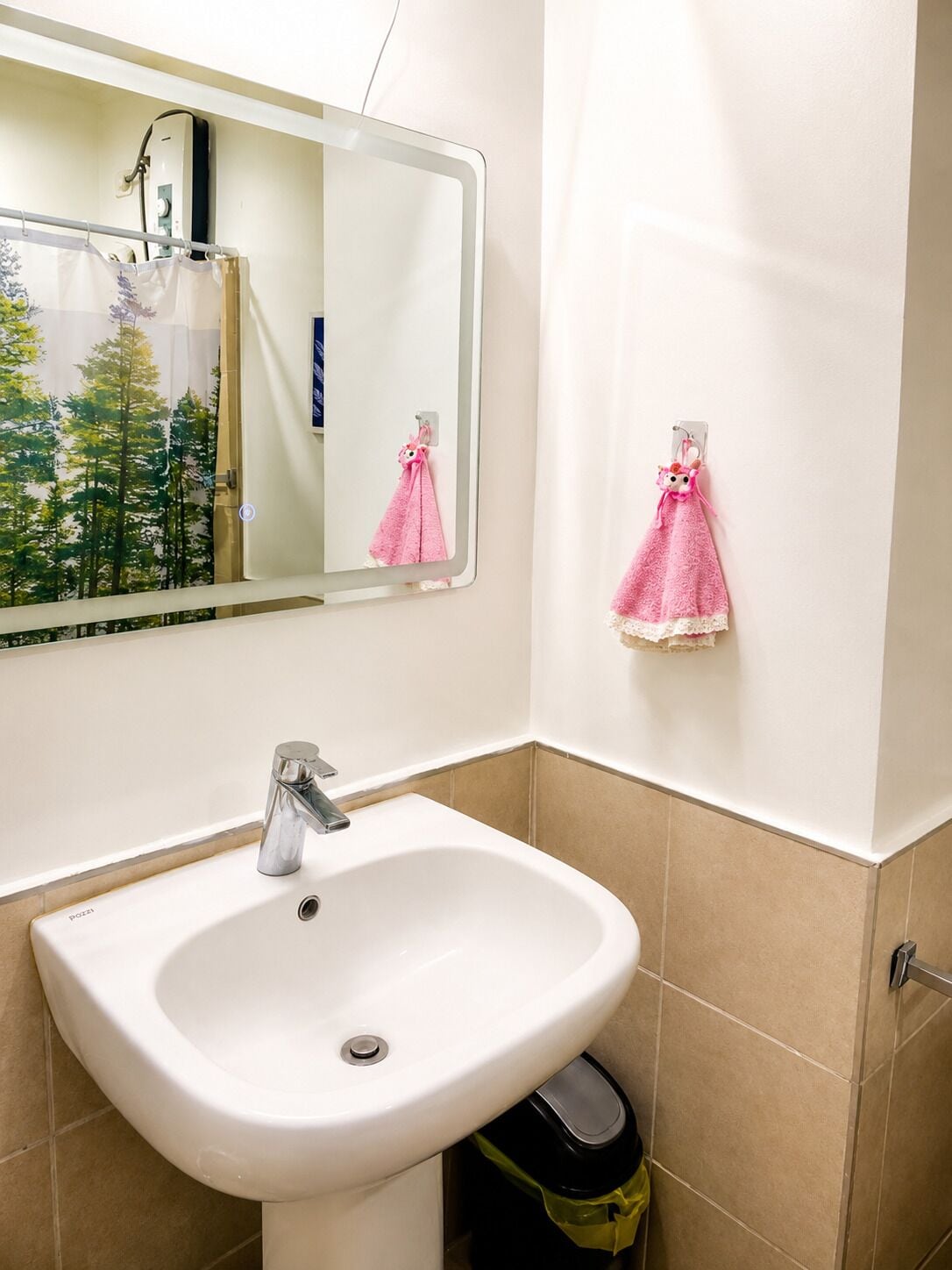 A bathroom with a white sink, a mirror, and two towels hanging on the wall.