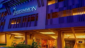 Entrada de hotel com design moderno, destacando uma placa e uma cobertura.