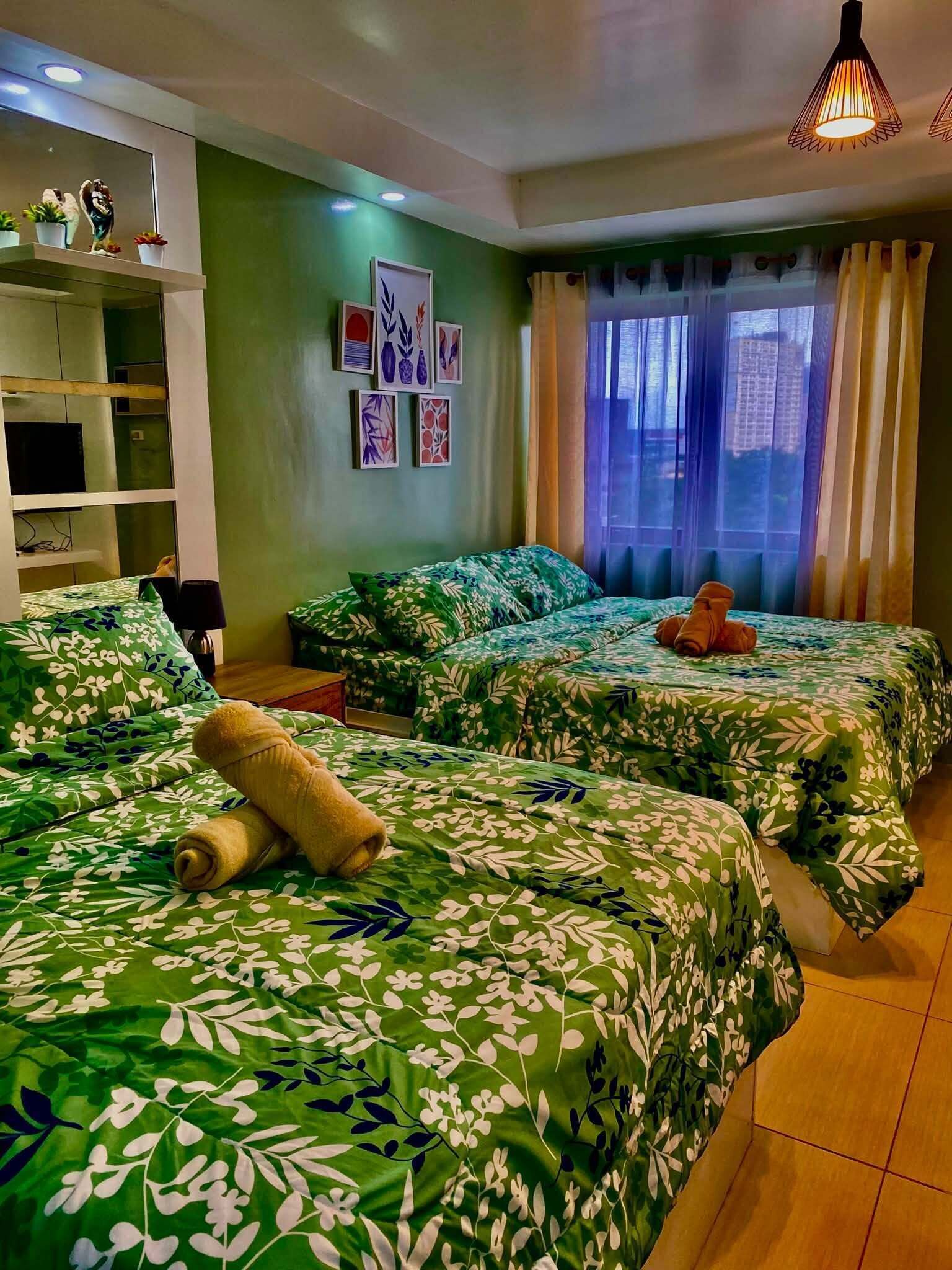 A hotel room with two beds, a sofa, a small table, and a window with curtains.
