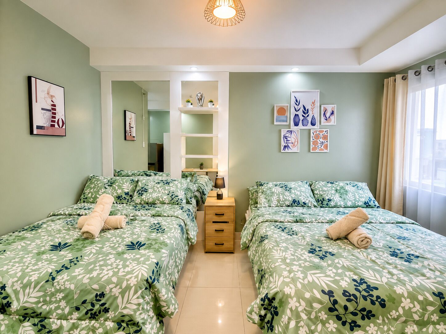 A hotel room with two beds, a small desk, a mirror, and artwork on the walls.