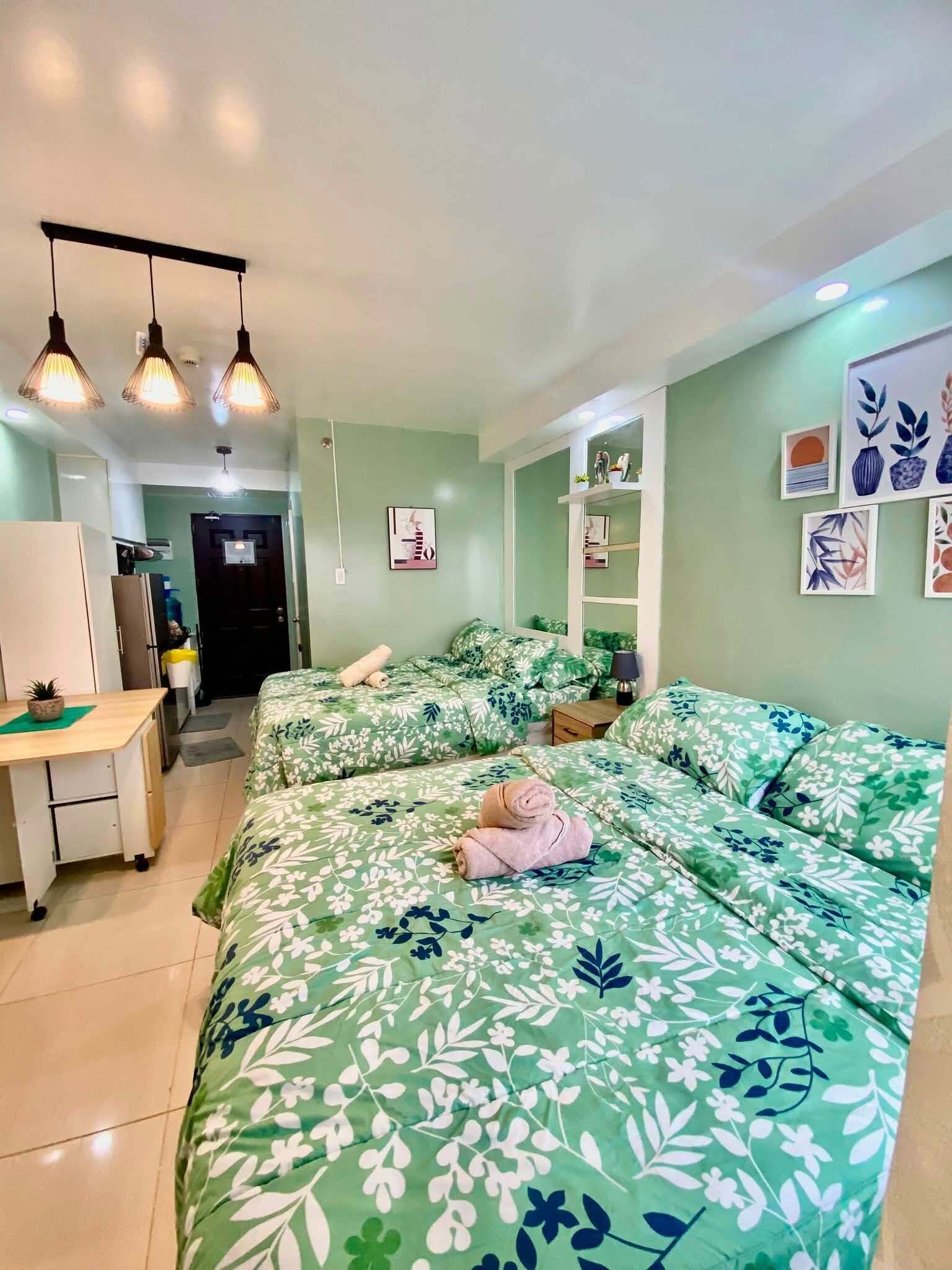 Una habitación con dos camas, un escritorio y una puerta que da a otra habitación.