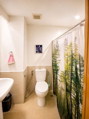 A bathroom with a toilet, sink, and shower curtain. - Near Sm And Ayala persimmon condo (Cebu City)