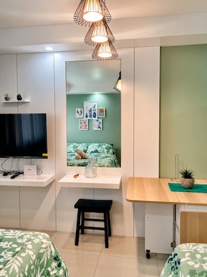 A modern bedroom with a bed, a desk, a chair, a TV, and a mirror. - Near Sm And Ayala persimmon condo (Cebu City)