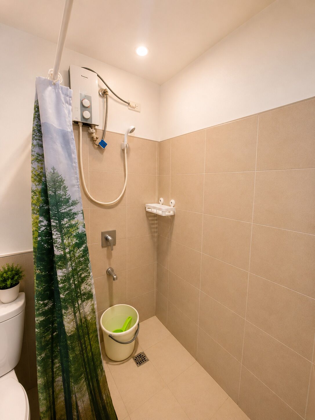 A small bathroom with a shower, a toilet, and a bucket.