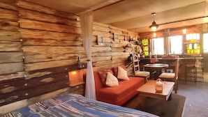 A cozy interior with wooden walls, a sofa, a table, and a bar area with bottles.