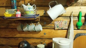 A kitchen with wooden walls, various kitchenware, a coffee maker, and a shelf with decorative items.