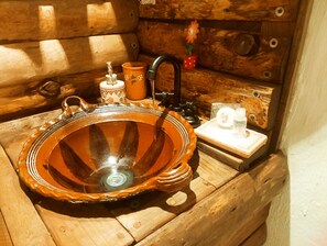 Een houten cabinestijl interieur met een rustieke houten wasbak, een klein oranje bakje en een decoratieve bloem.