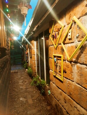 A narrow alleyway with stone walls, a wooden door, and a hanging lantern.