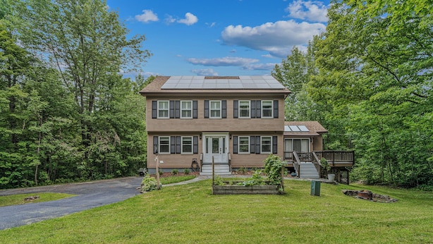 A two-story house with a front porch, a deck, and a fire pit in the yard. - Quechee Club Area Retreat | Game Room & Pets (Hartford)
