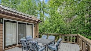 A deck with a table and chairs, surrounded by a wooden deck and glass doors leading to a covered area. - Quechee Club Area Retreat | Game Room & Pets (Hartford)