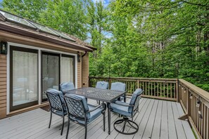 A deck with a table and chairs, surrounded by a wooden deck and glass doors leading to a covered area. - Quechee Club Area Retreat | Game Room & Pets (Hartford)
