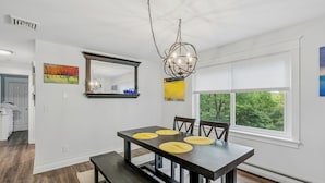 A dining area with a dark wooden table, four chairs, and a chandelier. - Quechee Club Area Retreat | Game Room & Pets (Hartford)