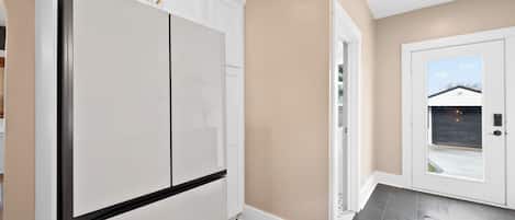 A modern kitchen with white cabinetry and a large refrigerator.