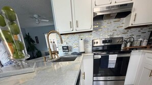 Eine moderne Küche mit weißen Schränken, einem Edelstahlbackofen und einer Marmorarbeitsplatte.