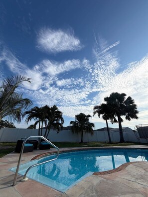 Una piscina con cielo sereno e palme.