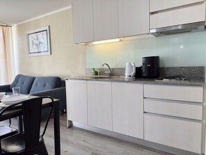 A modern kitchen with a built-in stove, a coffee maker, and a sink. - Oceana Suites Alberto Hurtado (Estación Central)