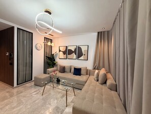 Sala moderna com sofá, mesa de centro de vidro e arte abstrata na parede.