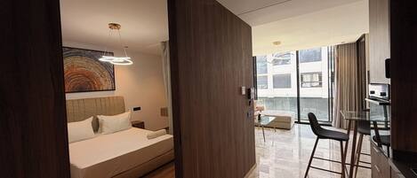 A modern hotel room with a large bed, a desk, and a view of the city.
