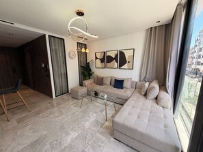 Una sala de estar moderna con un sofá modular, una mesa de centro de vidrio y arte abstracto en la pared.