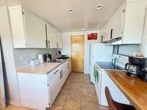 A compact kitchen with white cabinets, a built-in oven, a coffee maker, and a toaster.