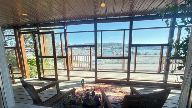 A covered outdoor seating area with a view of a waterfront and dock.