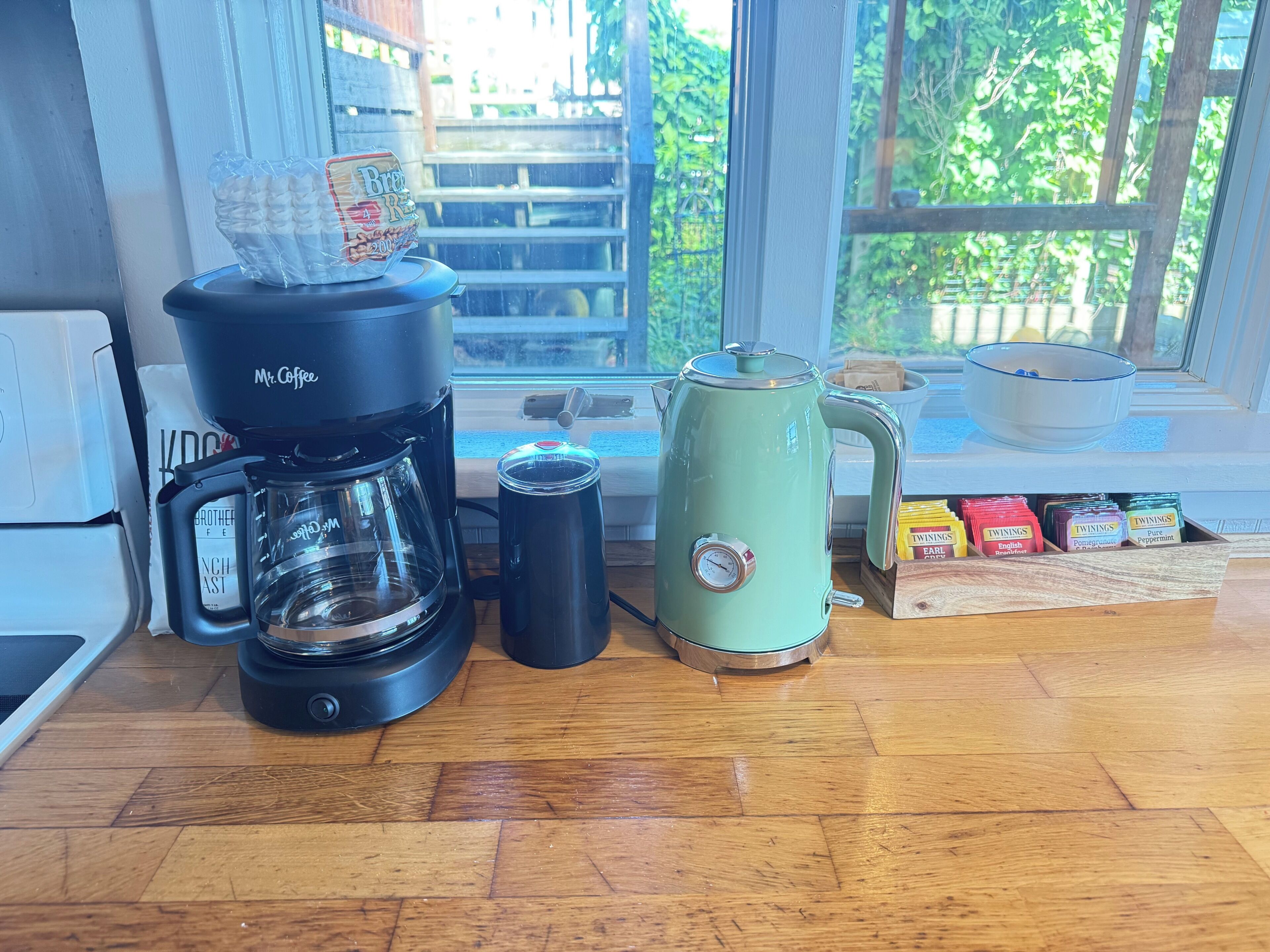 Un piano di lavoro in cucina con una macchina da caffè, un bollitore, una termosi e una scatola di tè Twinings.