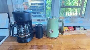 Un piano di lavoro in cucina con una macchina da caffè, un bollitore, una termosi e una scatola di tè Twinings.