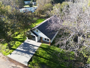 A single-story house with a garage, surrounded by trees and a grassy yard.