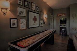 A room with a shuffleboard table, framed wildlife pictures, and a 'Hike Patrol' sign. - Modern Mountain View Cabin w Expansive Deck close to Cashiers (Glenville)