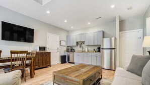 A modern kitchen with stainless steel appliances, a dining area with wooden furniture, and a living room with a large wooden coffee table. - Ponderosa Woods! Forest Hot Tub Escape by Monument (Monument)