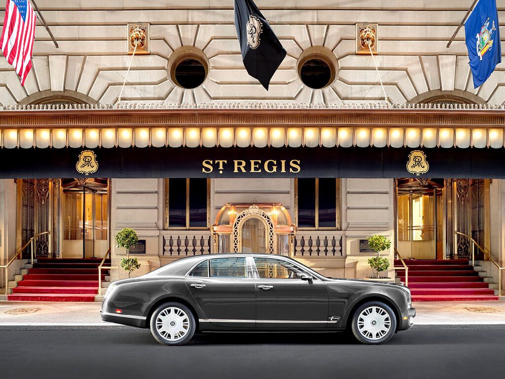 A luxury hotel with a grand entrance, a classic car parked in front, and a prominent sign reading 'ST REGIS'.