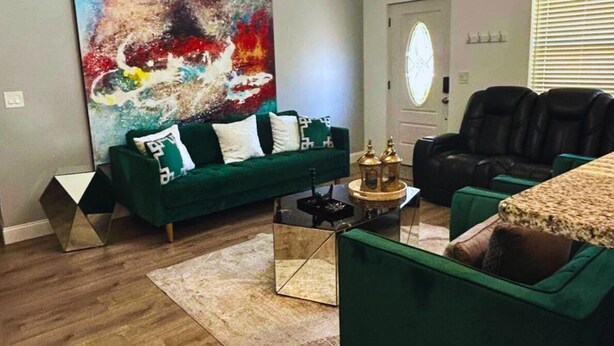 Sala de estar com um sofá verde, uma mesa de centro e uma grande pintura abstrata.