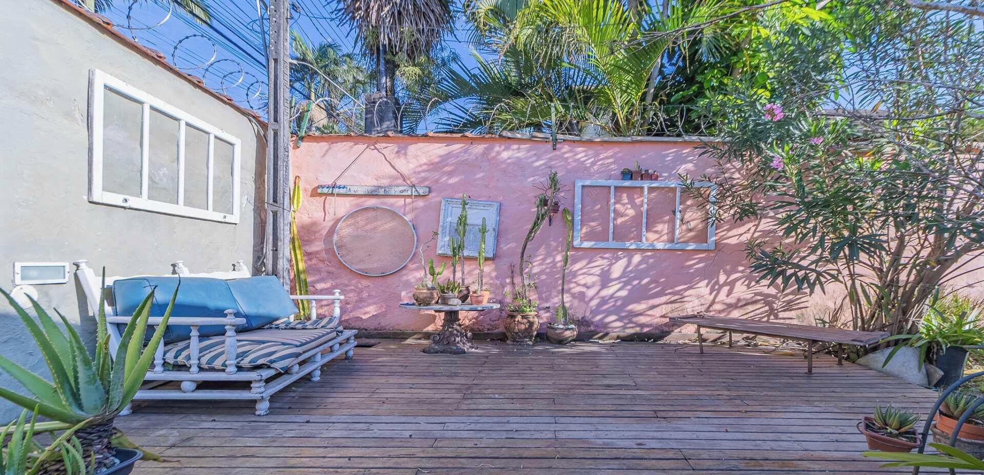 Une terrasse en bois avec un lit, une petite table et des plantes en pot.