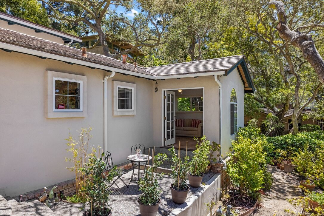A house with a covered patio, a small garden, and a door leading to an interior space.