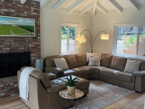 A living room with a sectional sofa, a small round table with a plant, and a fireplace.